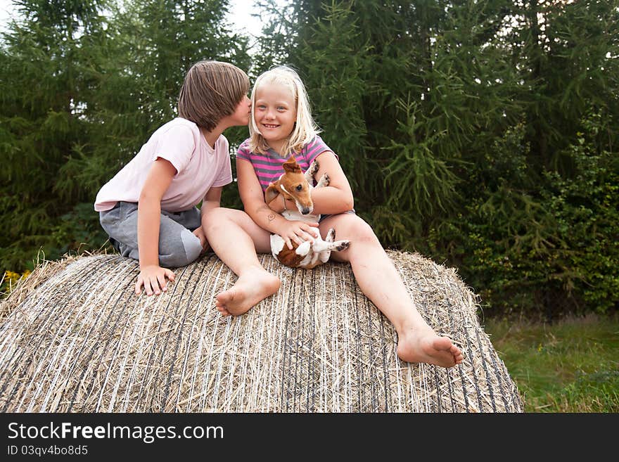 Two children and puppy, on huge bales of hay, and first kiss