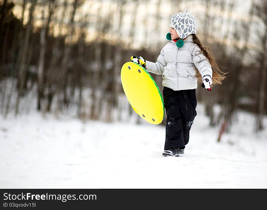 Cute little girl in warm clothes running in the snow with saucer in her hands. Cute little girl in warm clothes running in the snow with saucer in her hands