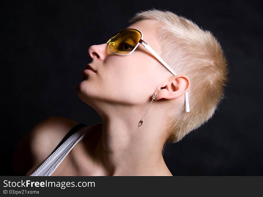 The young girl in yellow glasses on a black background