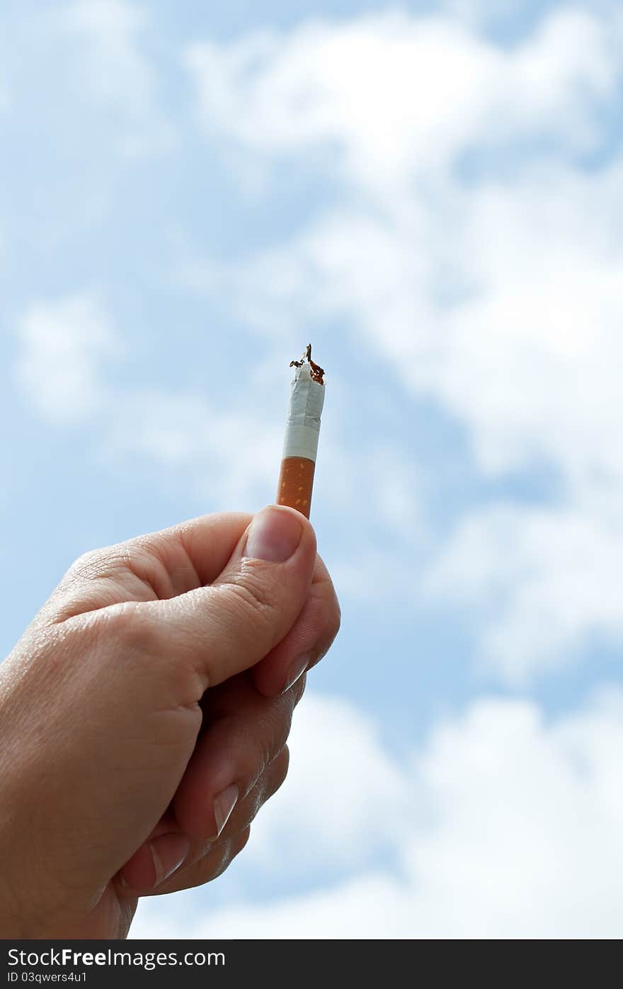 Holding a cigarette on the blue sky background