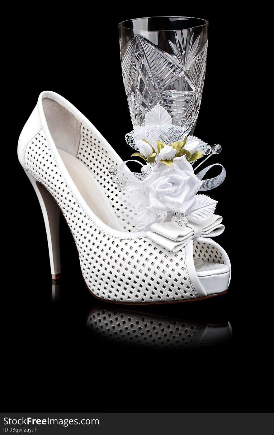 Crystal goblet and wedding shoe isolated on a black background