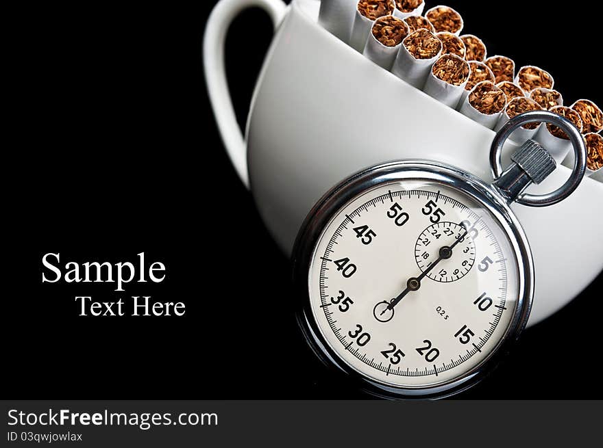 Cup full of cigarettes and stopwatch isolated on a black background. Cup full of cigarettes and stopwatch isolated on a black background