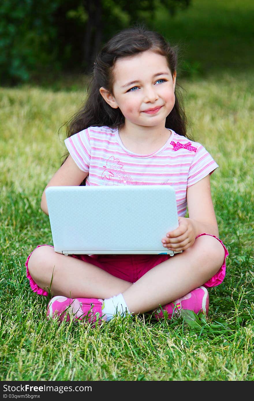 The small nice girl with the laptop on walk in park. The small nice girl with the laptop on walk in park