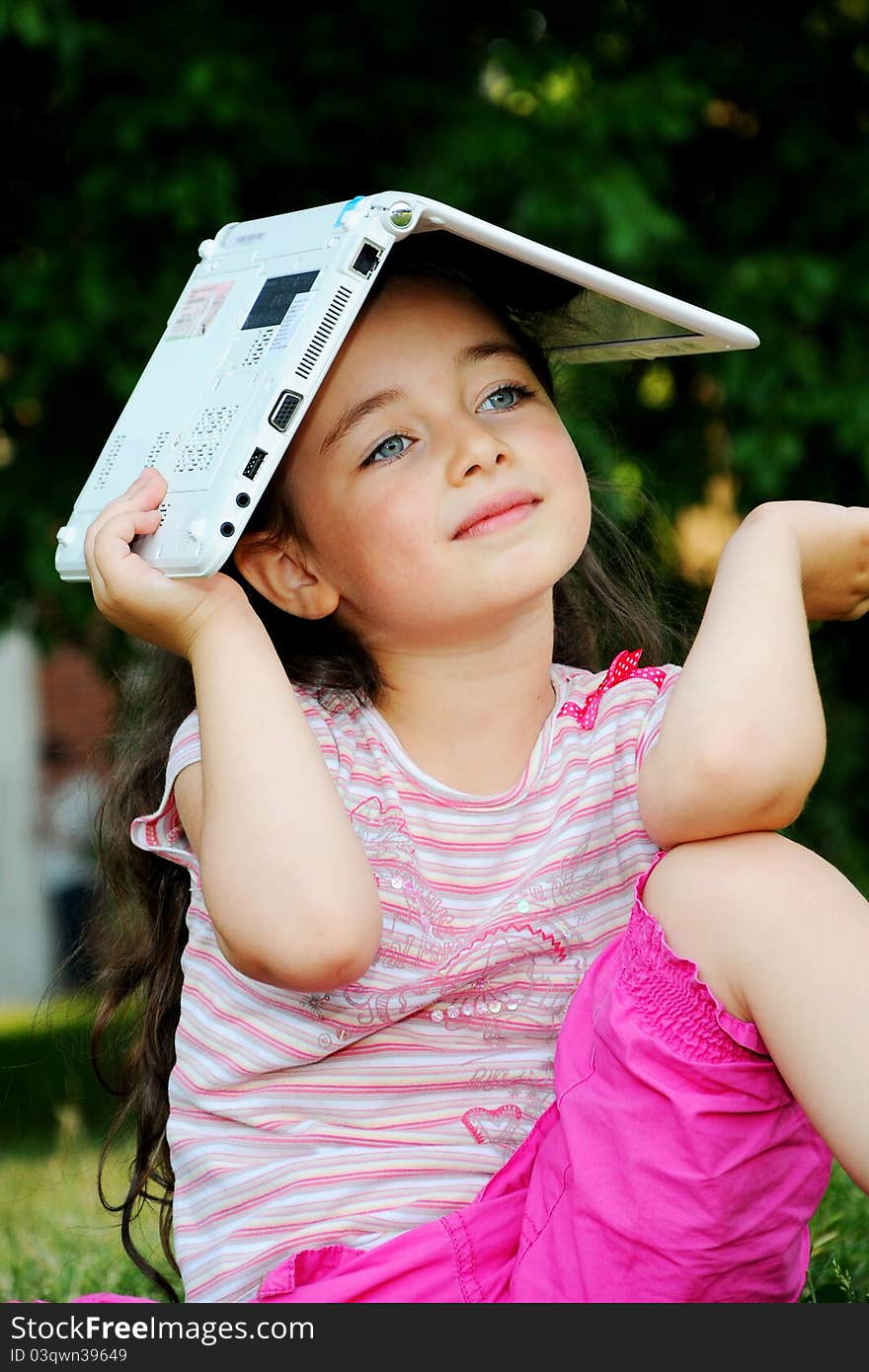 The small nice girl with the laptop on walk in park. The small nice girl with the laptop on walk in park