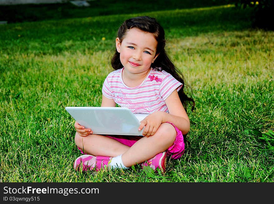 The small nice girl with the laptop on walk in park. The small nice girl with the laptop on walk in park