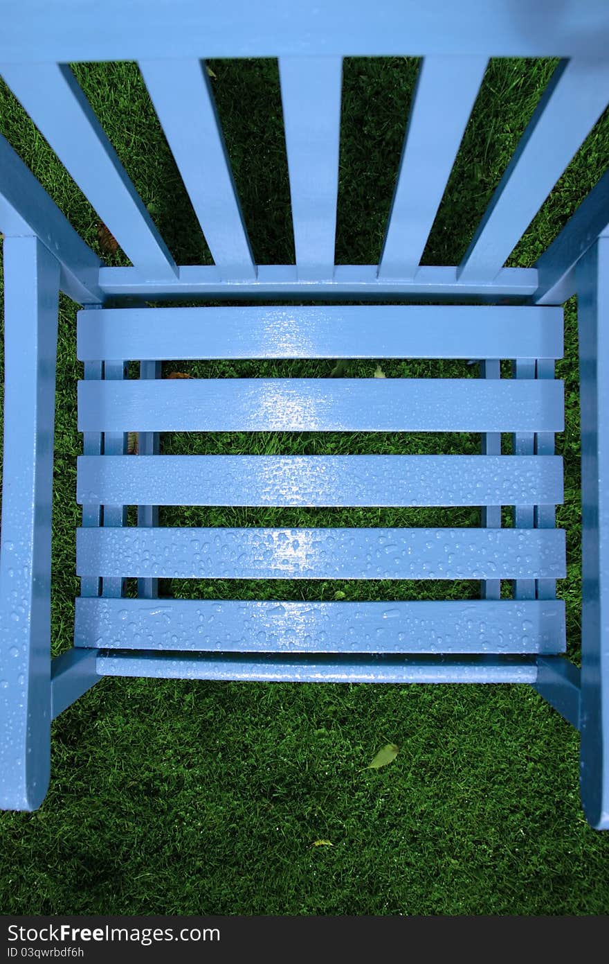 A wooden garden chair with rain drops on the surface. A wooden garden chair with rain drops on the surface