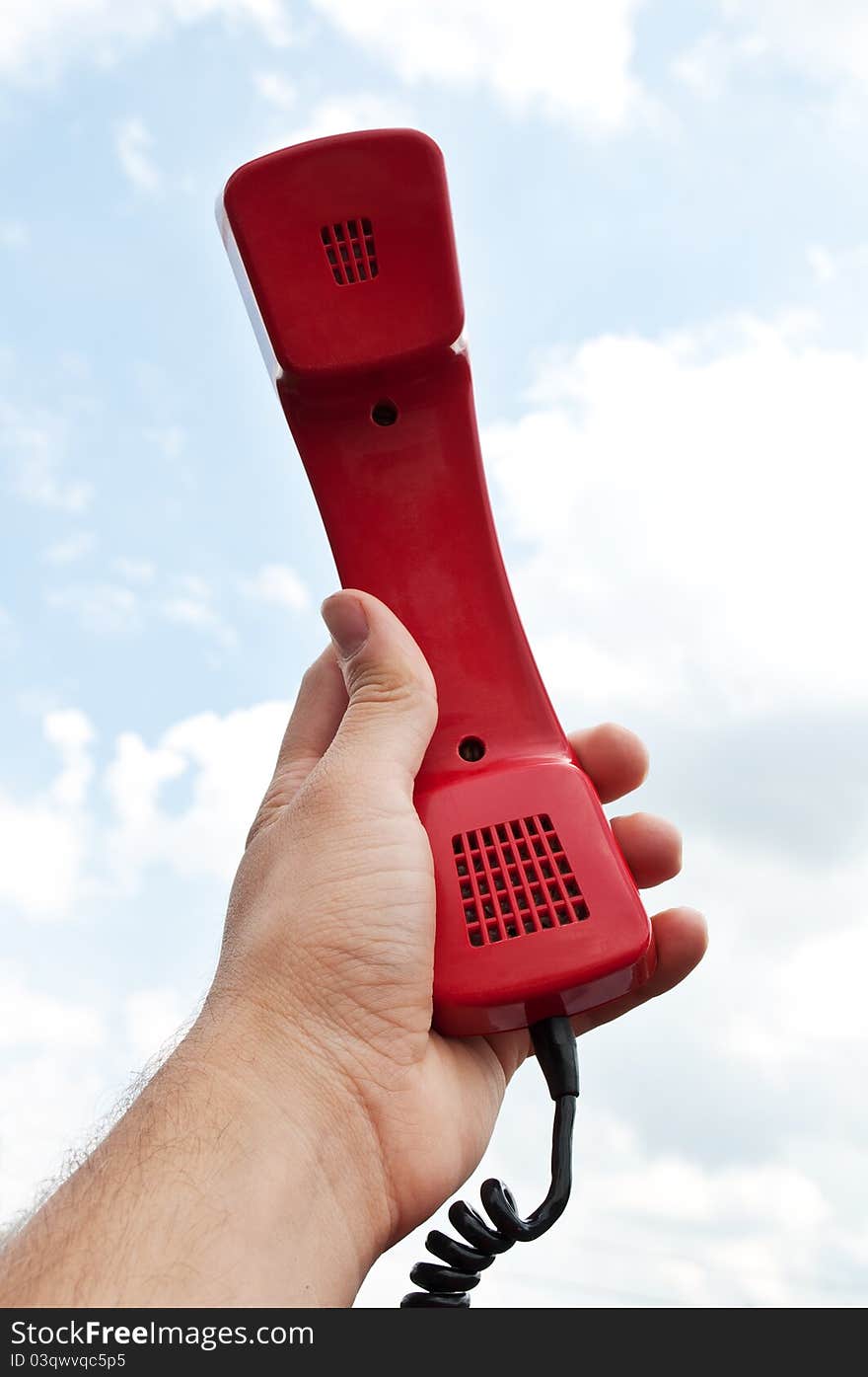 Man holding a red phone at the sky background