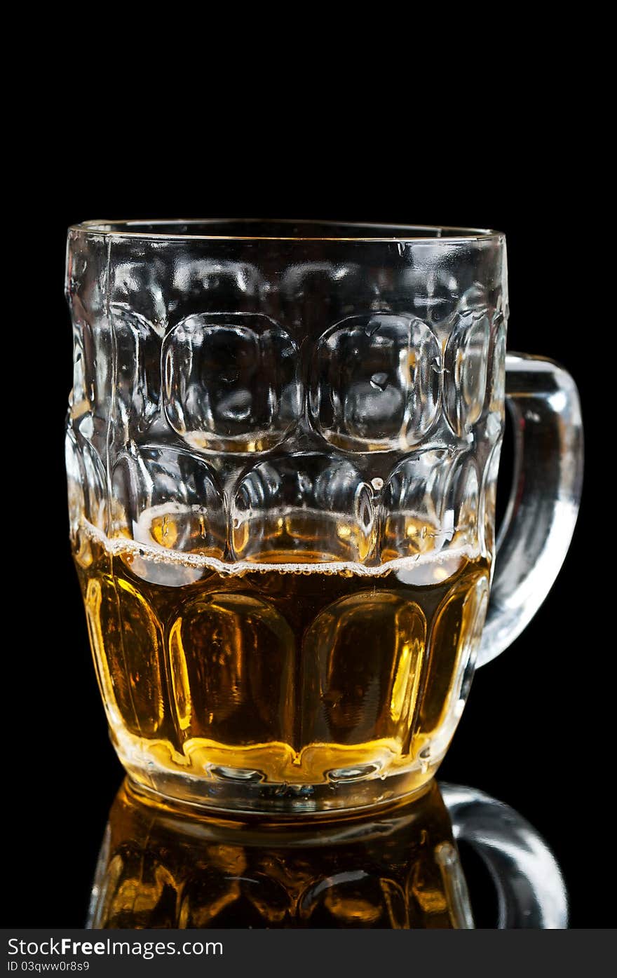 Half-full glass of beer isolated on a black background