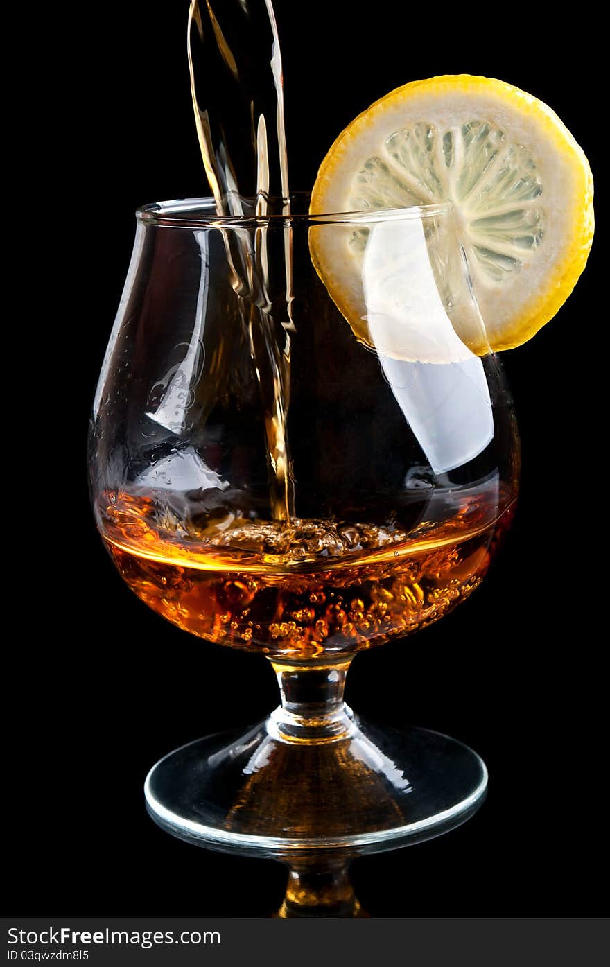 Cognac with lemon in a classic glass isolated on a black background