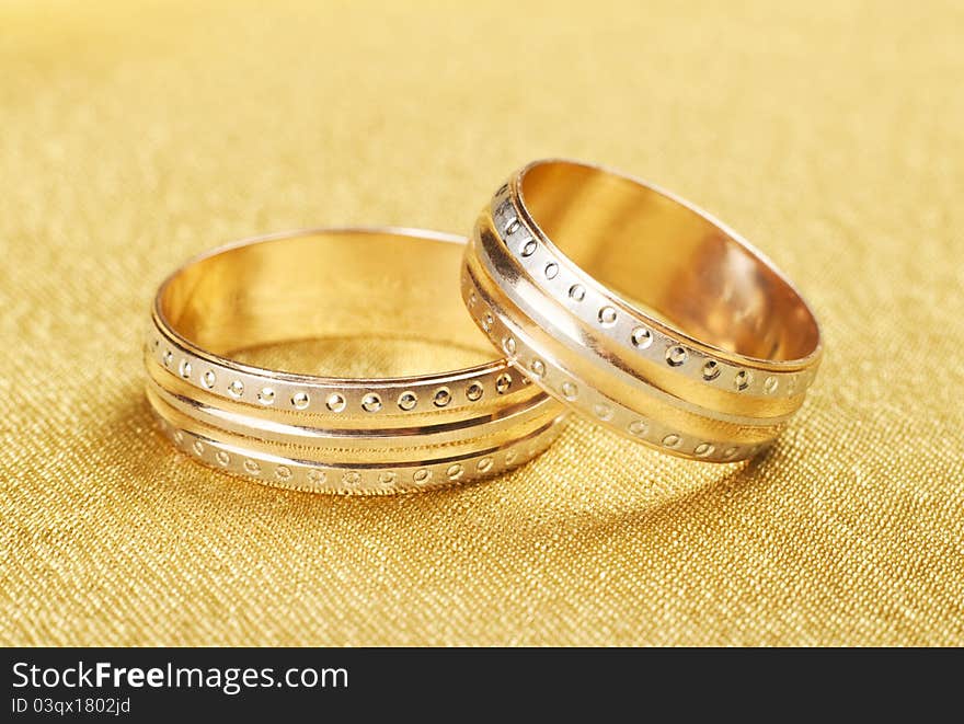 Gold wedding rings lying on silk