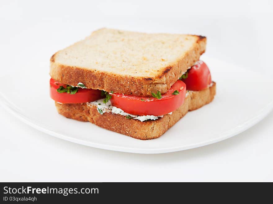 Sandwich with tomatoes and salty cheese on white plate. Sandwich with tomatoes and salty cheese on white plate