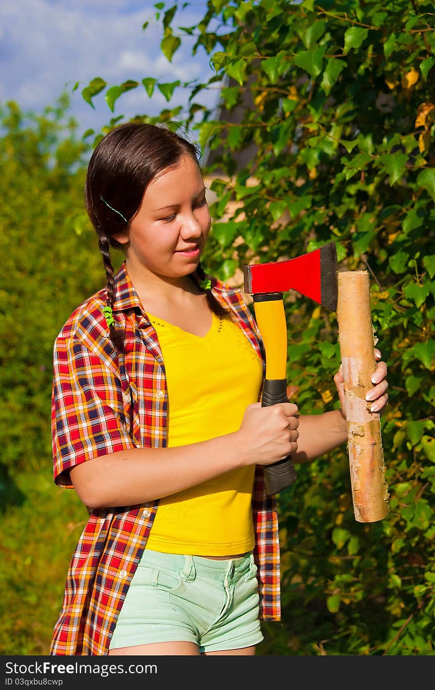 Young woman holding an axe and chock in the forest