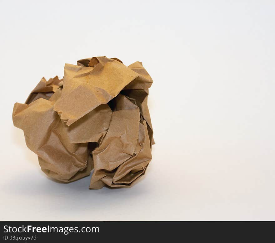 A crumpled piece of brown wrapping paper on a white background with copyspace. A crumpled piece of brown wrapping paper on a white background with copyspace.