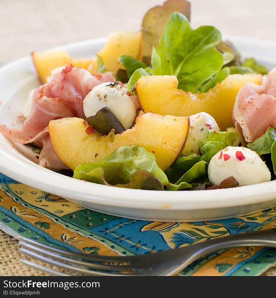 Fresh salad with peach, mozzarella cheese and ham. Selective focus