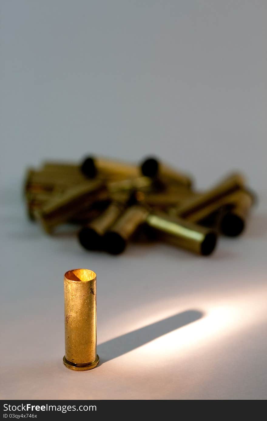 A group of emply .38 caliber brass shell casings with focus and spotlight on the front one. A group of emply .38 caliber brass shell casings with focus and spotlight on the front one.