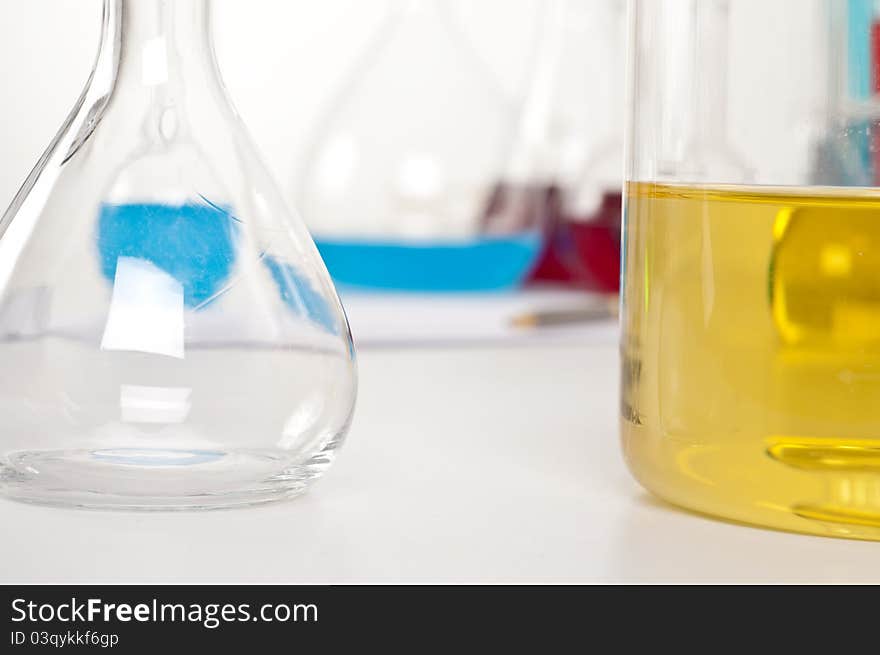 Flask with yellow liquid, in the background microscope and other items. Flask with yellow liquid, in the background microscope and other items