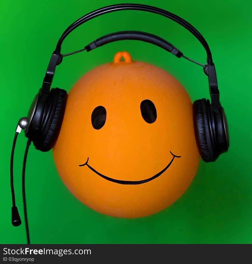 Inflatable orange ball Dj in earphone on green background