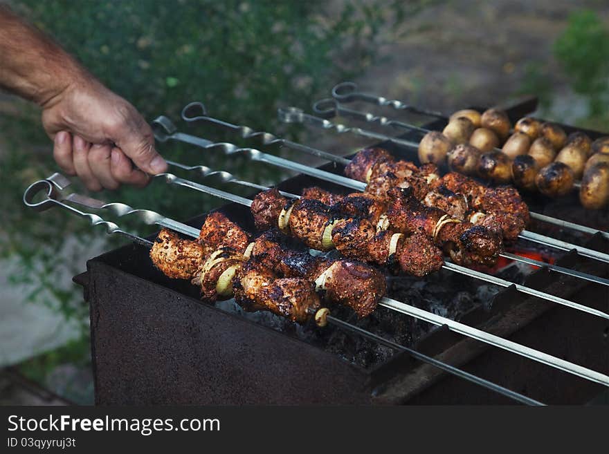 Shish kebab in process of cooking on open fire outdoors