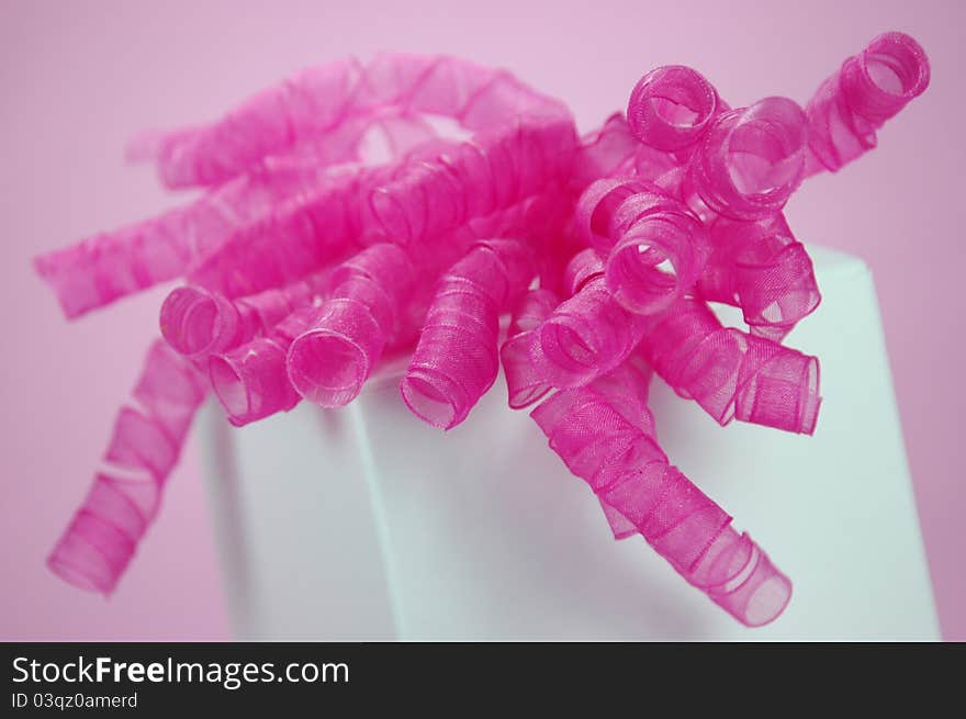 A white gift box with a bright fuchsia bow. A white gift box with a bright fuchsia bow