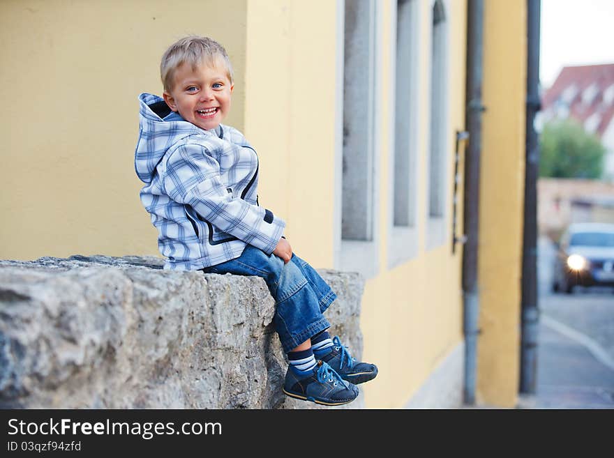 Little boy sits near the old house