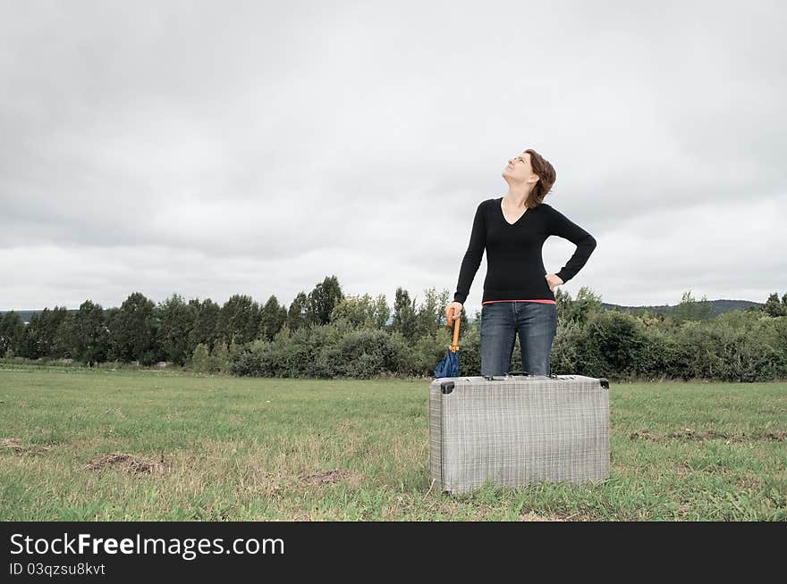 Young woman standing with suitcase and umbrella. Young woman standing with suitcase and umbrella