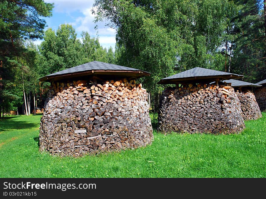 A photo of three piles of wood on the green grass