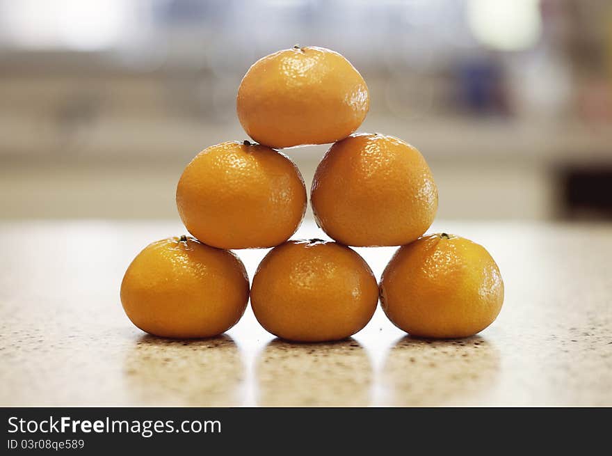 Six organic oranges stacked on kitchen countertop. Six organic oranges stacked on kitchen countertop