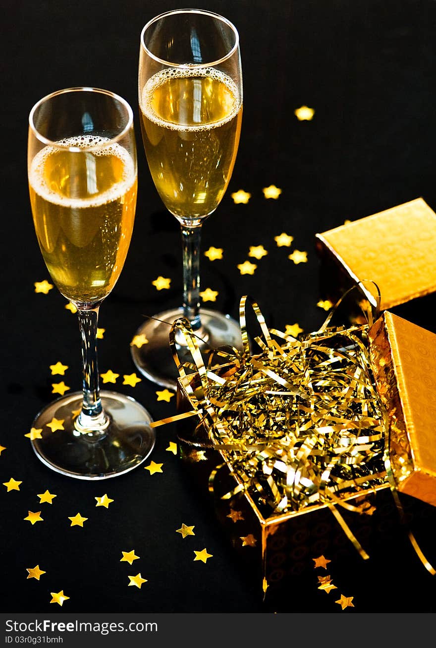 Two glasses of champagne with golden gift box