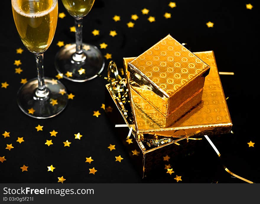 Two glasses of champagne with two golden gift boxes and star confetti. Two glasses of champagne with two golden gift boxes and star confetti