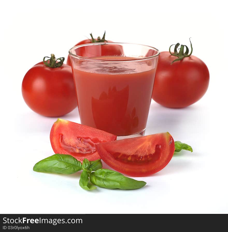 Glass of tomato juice and fruits with green leaves isolated on white