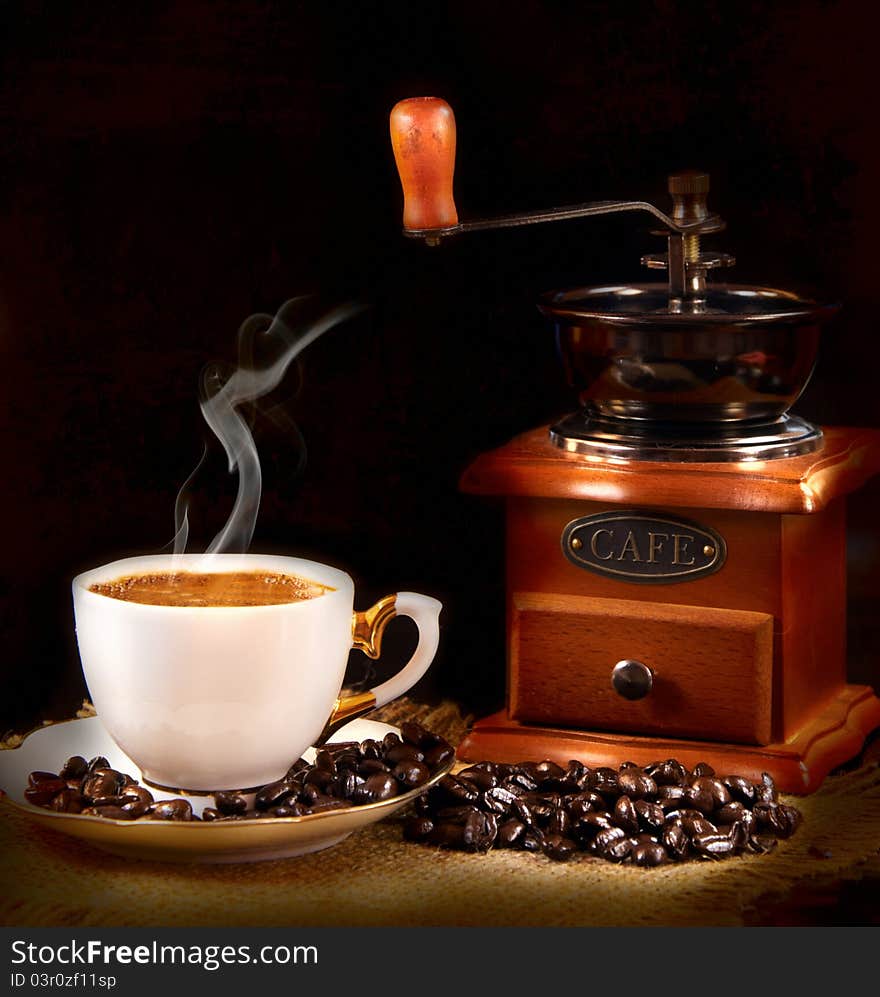 A cup of hot coffee and a coffee grinder. A cup of hot coffee and a coffee grinder