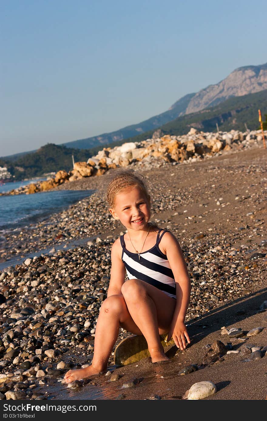 Beautiful girl sitting on a beach at the seashore