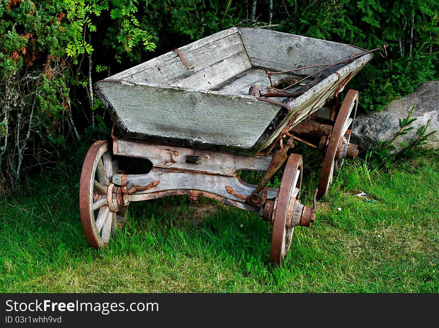 Old and used wagon standing near green bushes