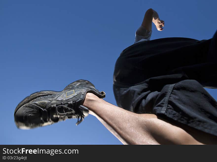 Runner jumping over blue sky