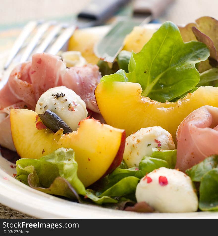 Fresh salad with peach, mozzarella cheese and ham. Selective focus