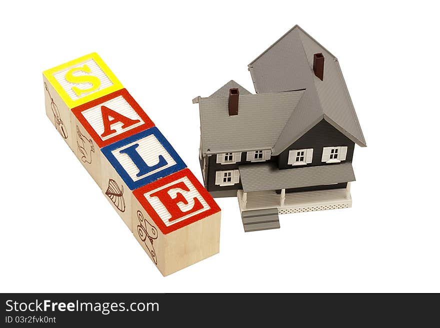 House model next to blocks spelling out the word sale. House model next to blocks spelling out the word sale.