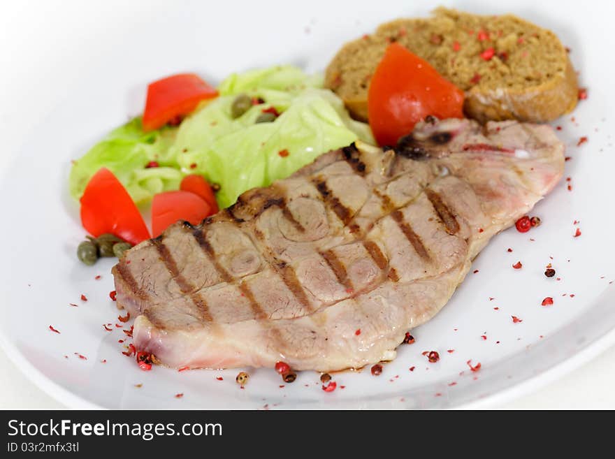 Tasty pork chop, grilled ,with salad,bun and tomato.