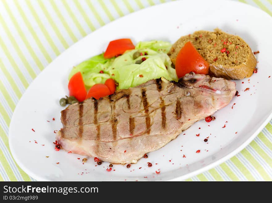 Tasty pork chop, grilled ,with salad,bun and tomato.