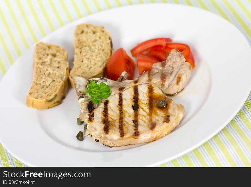 Tasty pork chop, grilled ,with salad,bun and tomato.