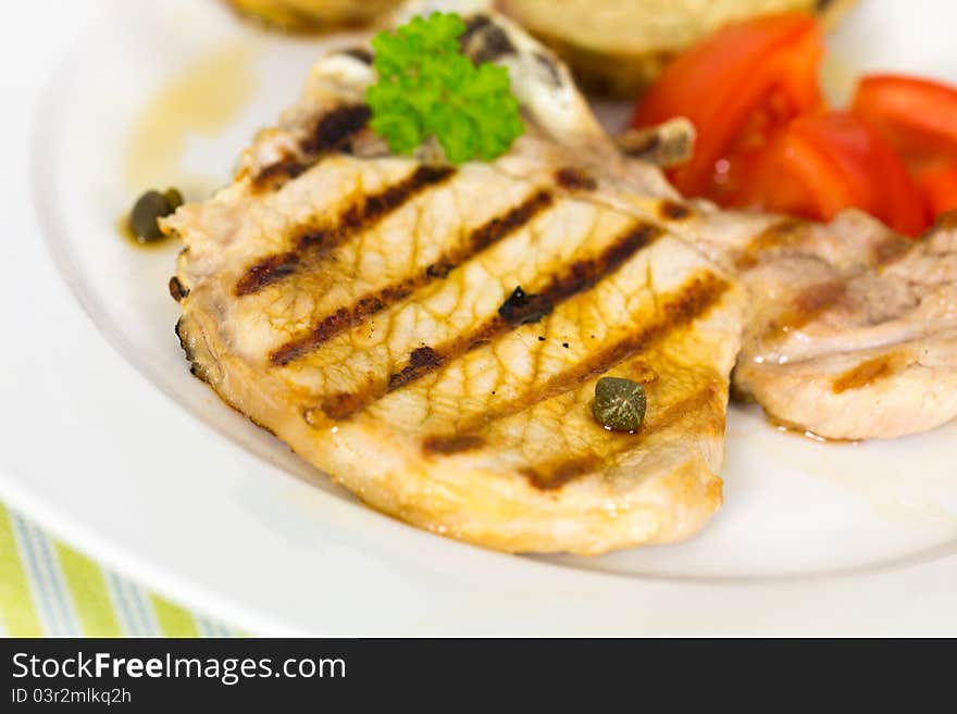 Tasty pork chop, grilled ,with salad,bun and tomato.