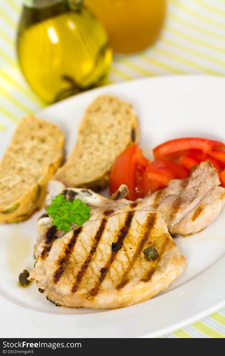 Tasty pork chop, grilled ,with salad,bun and tomato.