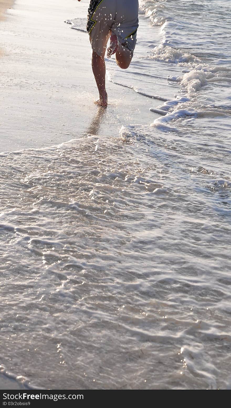 Feet and legs of man running on beach in golden afternoon light. Caribbean Sea, Cuba. Feet and legs of man running on beach in golden afternoon light. Caribbean Sea, Cuba