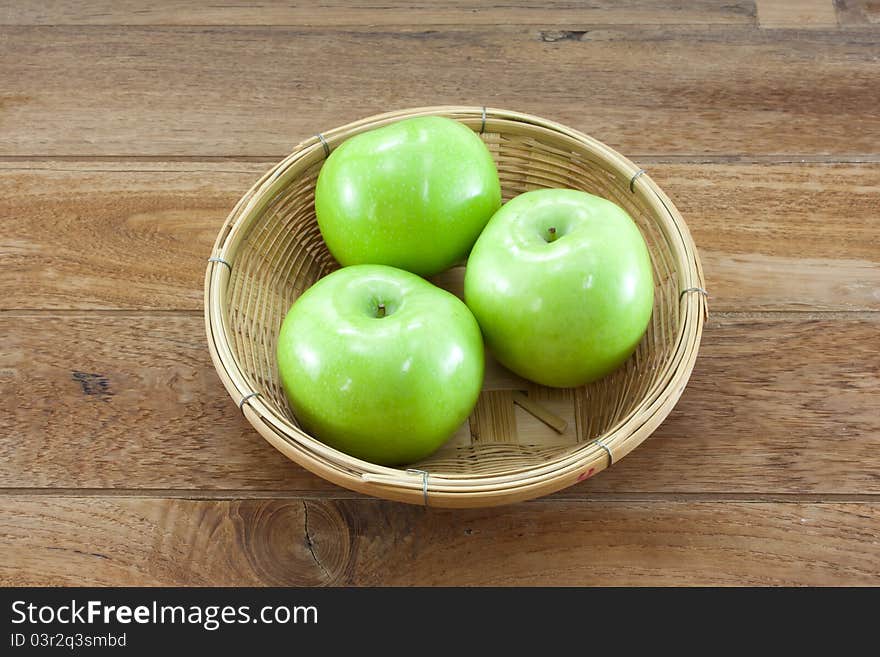 3 green apples on basket with teak wood background