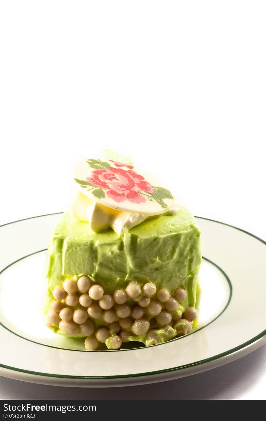 A piece of green cake with whipped cream and sugar on white background