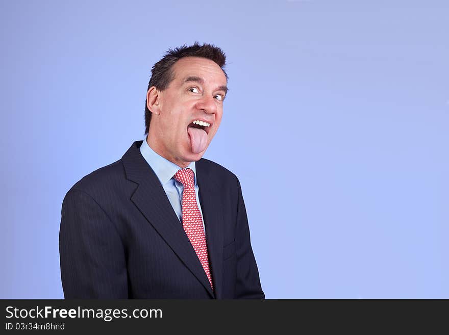 Attractive Business Man in Suit Sticking out Tongue on Blue Background. Attractive Business Man in Suit Sticking out Tongue on Blue Background