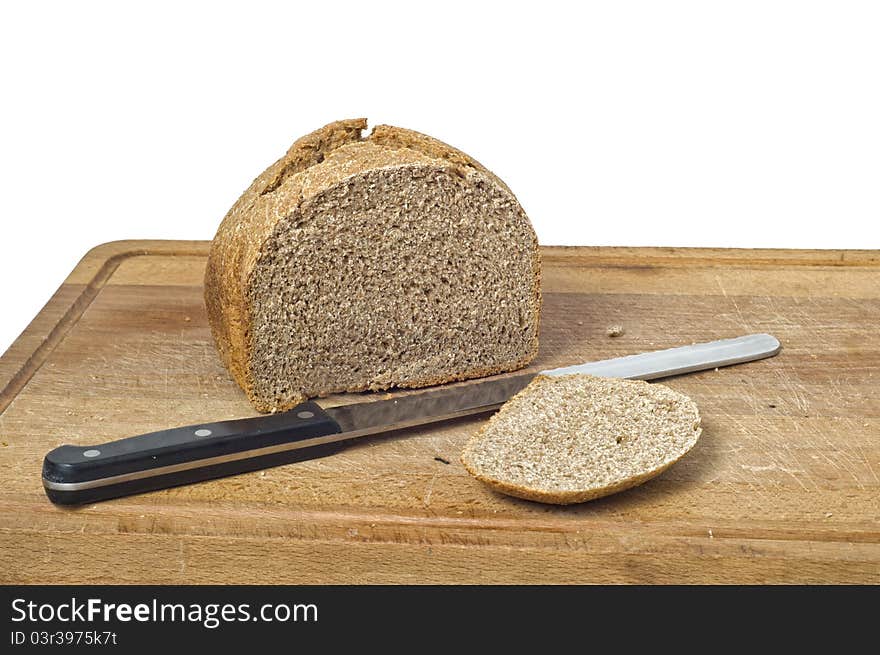 A home baked wholemeal loaf with bread knife and cutting board. Isolated on white background with path. A home baked wholemeal loaf with bread knife and cutting board. Isolated on white background with path.