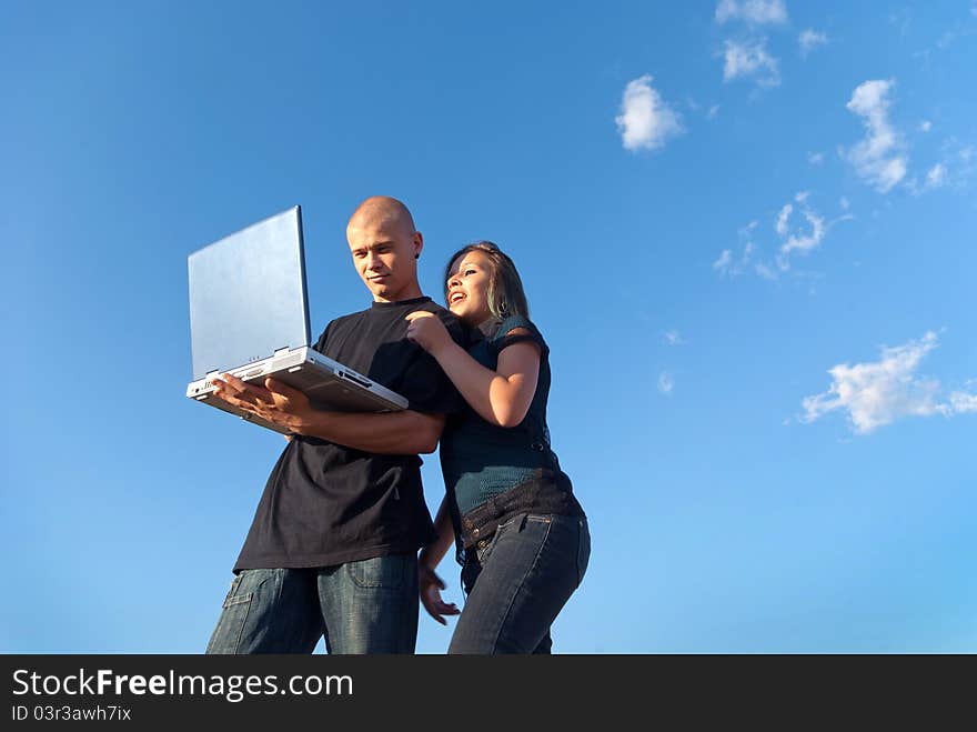 A young men working with laptop and smiling girl in the background sky with clouds. A young men working with laptop and smiling girl in the background sky with clouds