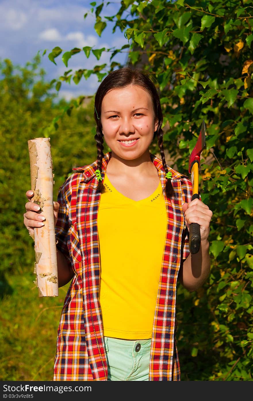 Young woman holding an axe and chock in the forest