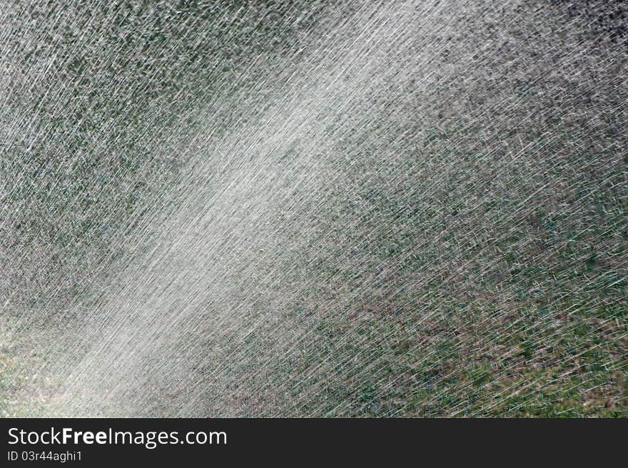 Water from an irrigation sprinkler head shooting droplets of water into the sunlight. Will make a good mobile phone or desktop background or abstract frame. Water from an irrigation sprinkler head shooting droplets of water into the sunlight. Will make a good mobile phone or desktop background or abstract frame.