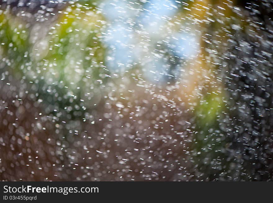 Water from an irrigation sprinkler head shooting droplets of water into the sunlight against a colorful bokeh background. Will make a good mobile phone or desktop background. Water from an irrigation sprinkler head shooting droplets of water into the sunlight against a colorful bokeh background. Will make a good mobile phone or desktop background.